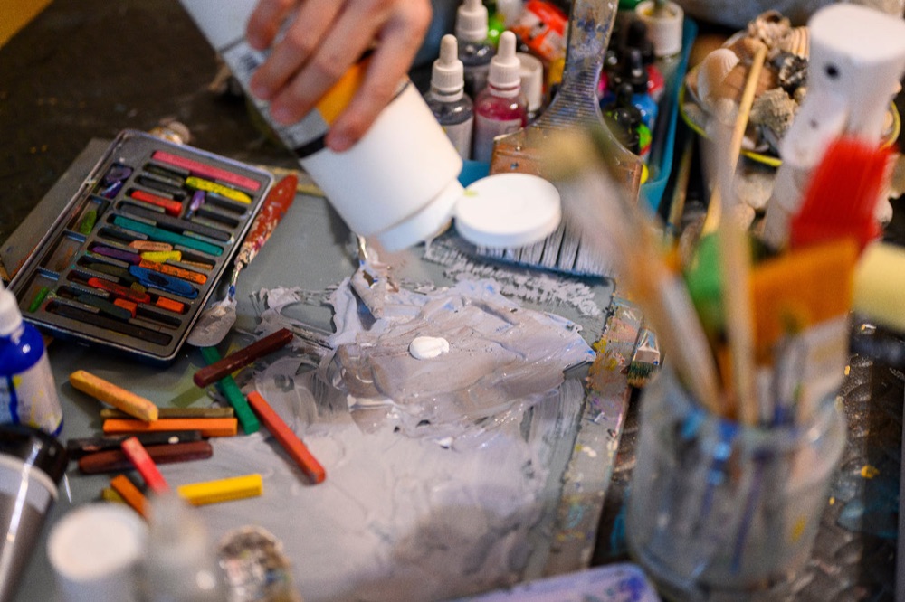 Detail of the painting process: pouring white acrylic over layers of colour